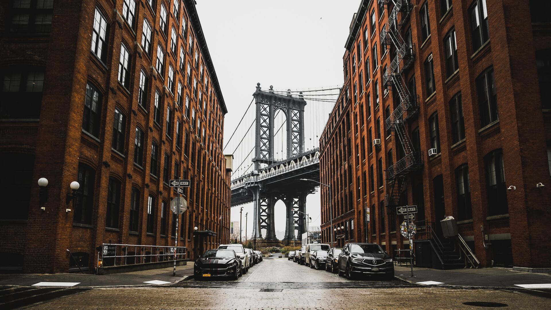 Brick buildings on the left and right side of the image give way to a view of the Brooklyn Bridge NYC